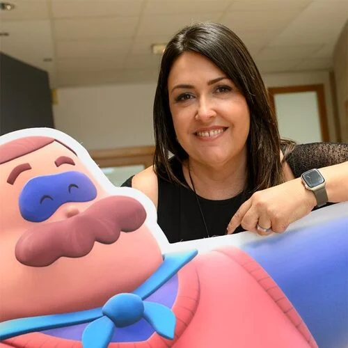 Nathalie Martínez señalando una figura troquelada del personaje animado SuperKlaus.